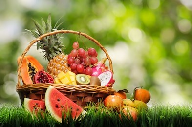 basket of tropical fruits on green grass.