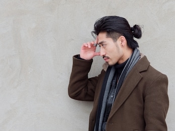 portrait of chinese young mustached man put his hand on his forehead with gray wall background, thinking, side view.