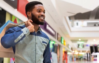 happy black guy in shopping mall, panorama, copy space