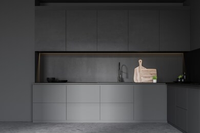 interior of minimalistic kitchen with dark gray walls, concrete floor, gray countertops with built in sink and black cupboards with dishes and cutting boards. 3d rendering