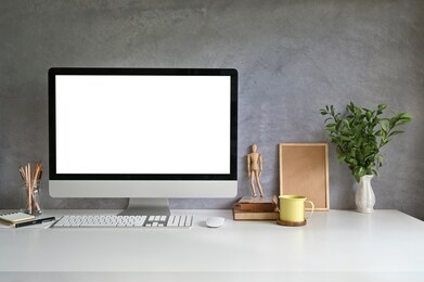 pc computer on workspace with coffee mug, pencil, books and plant on office desk.