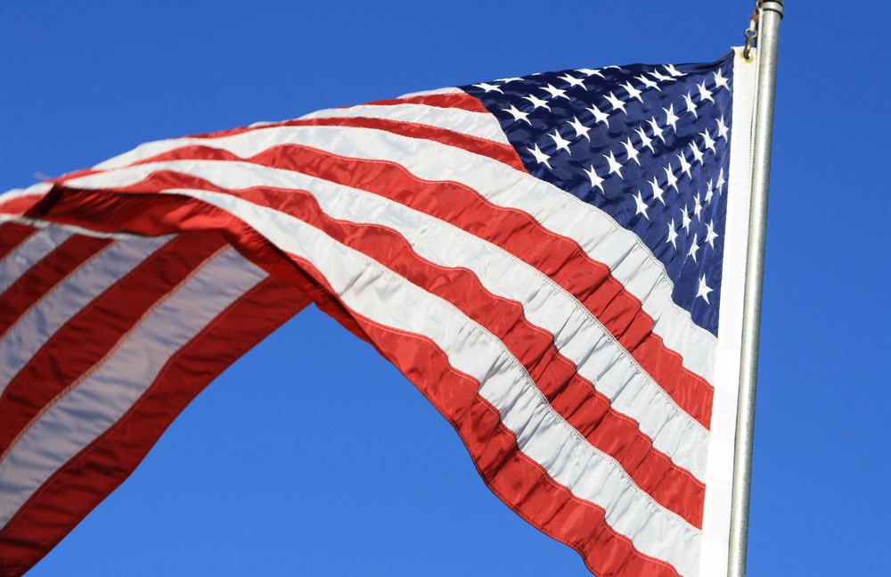 the flag is flying beneath a brilliant blue sky.