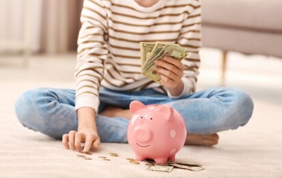 teen girl with piggy bank and money at home, closeup