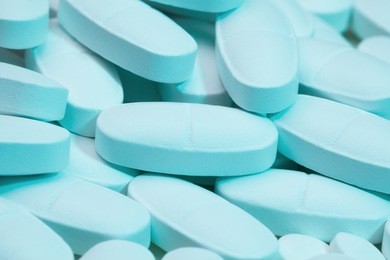 close-up of pile of white bluish long tablets laying on white tablets