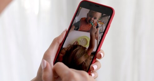 woman hand with smartphone showing kid picture on white background