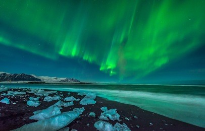 a beautiful aurora display over the ice beach near jokulsarlon, iceland.