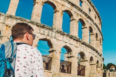 young man tourist standing near old roman coliseum in pula croatia. tourism concept. background. copy space