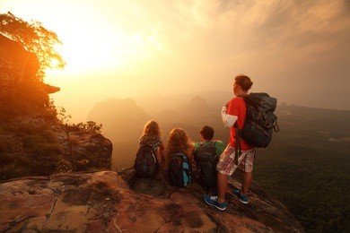 group of hikers relaxing on top of a mountain and enjoying sunrise
