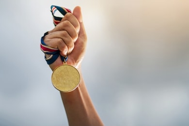 hand holding gold medal on sky background, the winner and successful concept