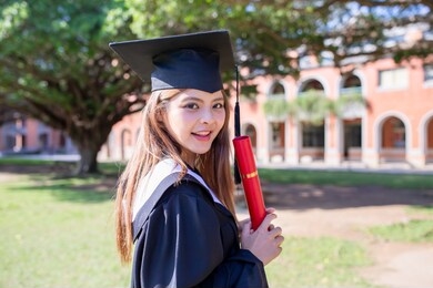 pretty girl gratuate happily at campus with diploma holding in her hand