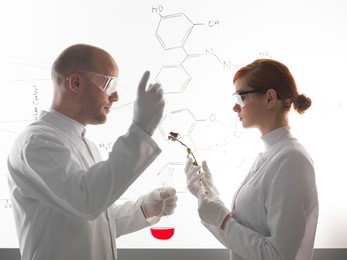 two young scientists wearing medical protection uniform while making a chemical experment