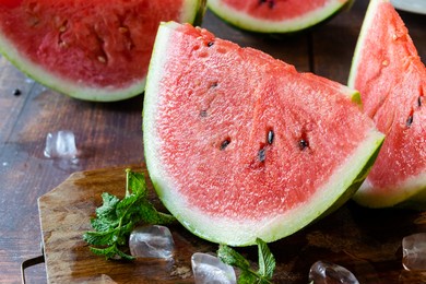 slices of watermelon with ice cubes and mint leaves on a brown chopping board and a wooden table.