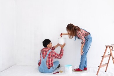 young asian couple in yom-bear and plaids shirts in concept couple help painting a new color the room renovation in thailand