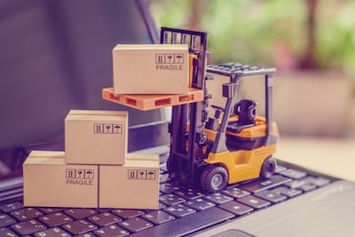 logistics, supply chain and delivery service concept : fork-lift truck moves a pallet with box carton. boxes on a laptop computer, depicts wide spread of products around globe in ecommerce booming era