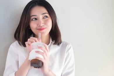 happy smiling asian woman drinking iced bubble milk tea; aka boba tea, pearl milk tea, tapioca tea, asian exotic beverage concept; retouched image