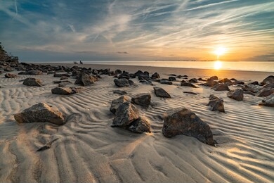 stunning clouds cover the sky during sunset at jekyll island, ga showing the beautiful beach stones.