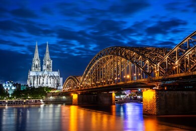 night in cologne at the river rhine with the illuminated cathedral and the hohenzollern bridge.