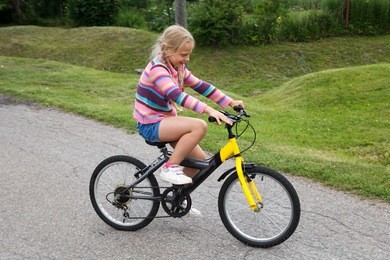 little girl learning to ride a bicycle on empty street