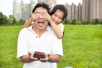 surprised father holding gift box from little girl for father's day