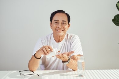 portrait of elderly asian man taking medicine every day