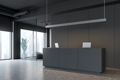 corner of modern office with gray and white walls, concrete floor, gray reception table with computers and white waiting room with grey pouffes. 3d rendering