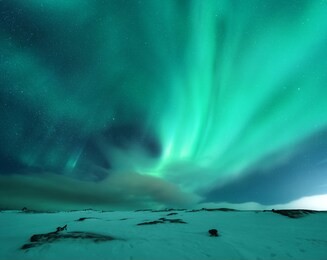 aurora borealis above the snow covered mountain hill in europe. beautiful northern lights in winter. night landscape with green polar lights and snowy mountains. starry sky with aurora. nature. space