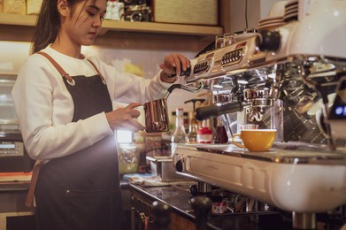 coffee business concept.asian woman barista wear blue apron holding hot coffee cup 
