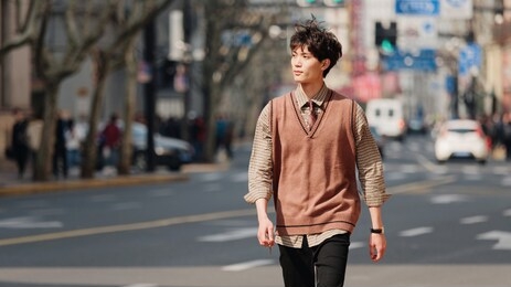 portrait of a handsome chinese young man with korean style clothes walking on street in hurry in sunny day with shanghai nanjing road background, male fashion, cool asian young man lifestyle.