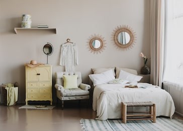 scandinavian modern cozy interior. wide bed with pillows, armchair and decorations in bedroom. real photo