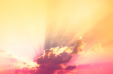 bright sun behind neon light pink clouds with orange light and sun rays