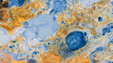 top down aerial view from drone on geothermal icelandic area in iceland seltun near krysuvik and kleifarvant lake, blue water and orange colorful ground texture structure hot spring and mud background