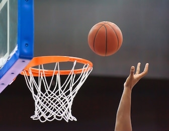 orange basketball ball flying into the basketball hoop