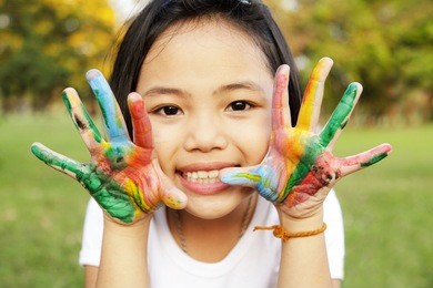 little girl with hands painted in colorful paint