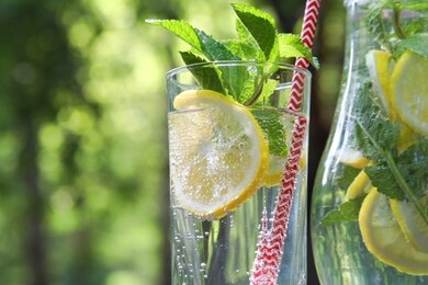 lemonade in glass, jug with sliced lemons, limes, mint. cold drink in hot summer day. close up, with copy space.
