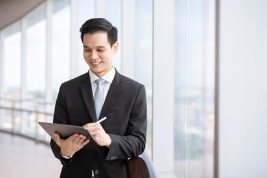 portrait of confident modern young businessman wear black suit hand holding digital tablet. 