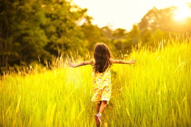 little girl running on meadow with sunset