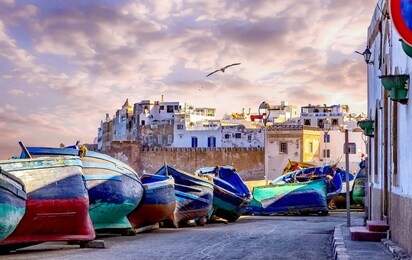 the old town of essaouria surrounded by the wall of the fortress,in the foreground with famous blue wooden fishing boats. essaouira is one of the unesco world heritage site.