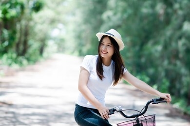 portrait of young beautiful woman riding a bicycle in a park.