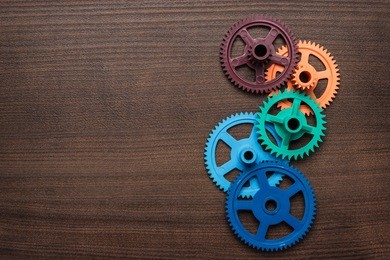 colorful gears on the brown wooden background