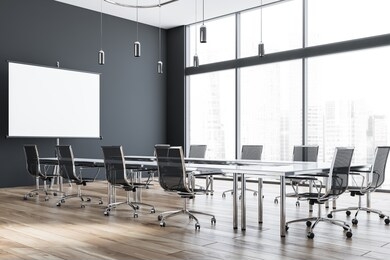 interior of modern office meeting room with grey walls, wooden floor and glass conference table with black chairs and mock up projection screen. 3d rendering