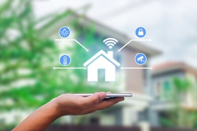 hands holding smart phone with app smart home on blurred house as backgrounds