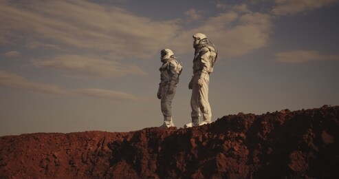 medium shot of two astronauts pointing and looking away on mars