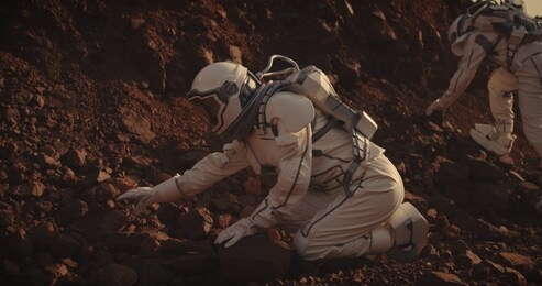 medium long shot of two astronauts collecting rock samples on mars