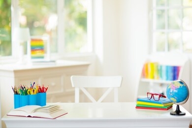 back to school. kids bedroom with wooden desk, books, globe, backpack, glasses and pencils. white room with big window for young child. home interior for girl or boy. table for homework and study.