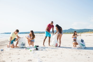 group of activists friends collecting plastic waste on the beach. people cleaning the beach up, with bags. concept about environmental conservation and ocean pollution problems