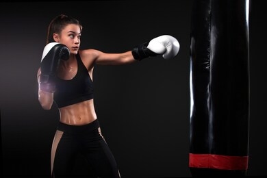 woman boxer fighting in gloves with boxing punching bag on black background. boxing and fitness concept.