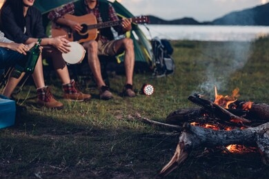 camping tent camp in nature happy friends group night party bonfire and playing guitar together in summer at nature forest