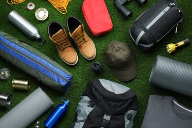 flat lay composition with different camping equipment on green grass