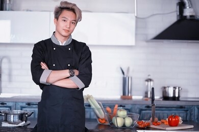 a young asian cook in the kitchen prepares food in a cook suit
