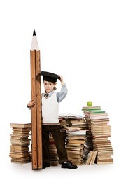 a boy standing near the pile of books and holding a huge pencil. education. isolated over white.